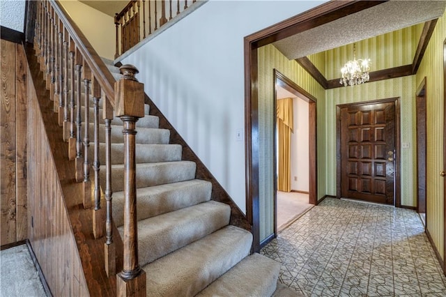 entryway with a notable chandelier, wallpapered walls, stairs, and baseboards