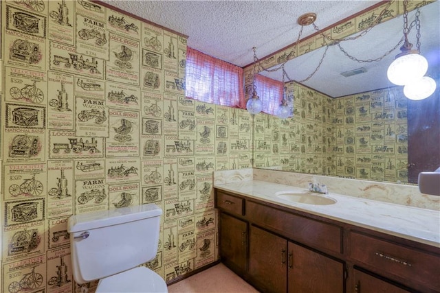 bathroom with vanity, visible vents, wallpapered walls, a textured ceiling, and toilet