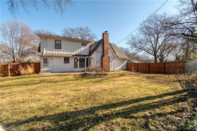 back of house featuring a chimney, a yard, and fence