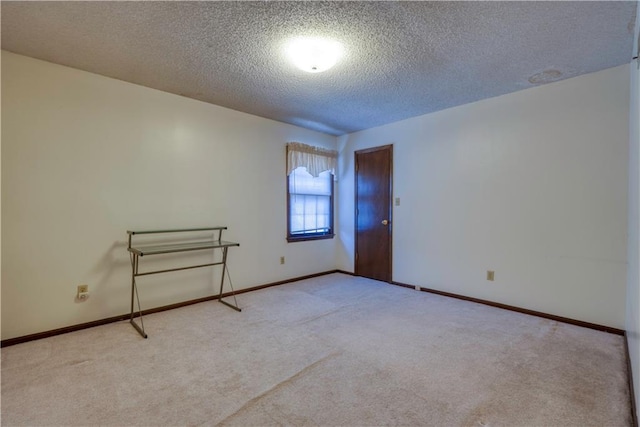 spare room with baseboards, carpet, and a textured ceiling