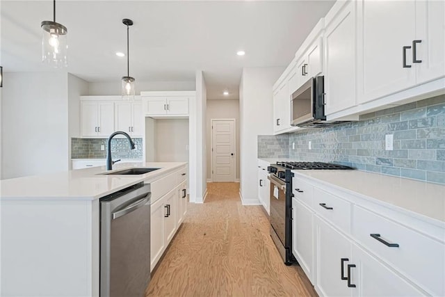 kitchen featuring sink, decorative light fixtures, a center island with sink, white cabinets, and appliances with stainless steel finishes