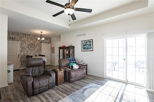 living room featuring wood walls, hardwood / wood-style floors, and ceiling fan with notable chandelier