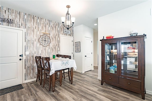 dining space with dark hardwood / wood-style flooring, a notable chandelier, and wood walls