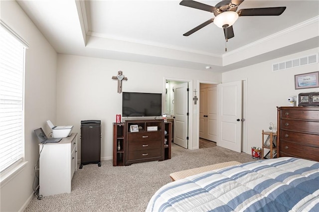 bedroom featuring light carpet, a tray ceiling, ceiling fan, and ornamental molding