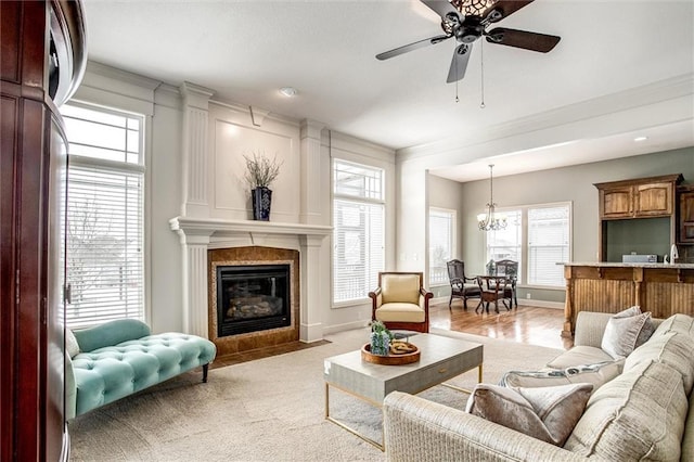 living room with light carpet, a fireplace, crown molding, and ceiling fan with notable chandelier