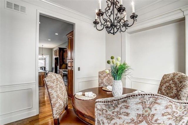 dining space with dark hardwood / wood-style flooring, crown molding, and a chandelier