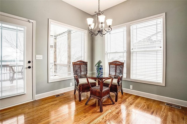 dining area with plenty of natural light, light hardwood / wood-style floors, and an inviting chandelier