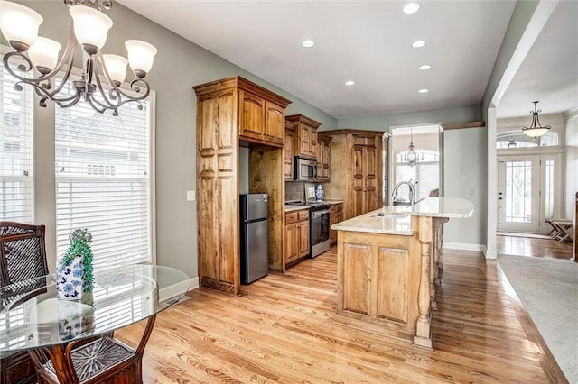 kitchen with light stone countertops, pendant lighting, stainless steel appliances, and a notable chandelier