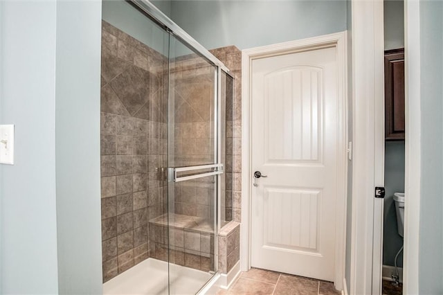 bathroom featuring tile patterned flooring, toilet, and an enclosed shower