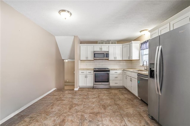 kitchen featuring appliances with stainless steel finishes, backsplash, white cabinetry, and sink