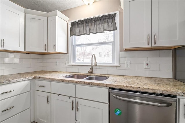 kitchen featuring stainless steel dishwasher, white cabinets, sink, and tasteful backsplash