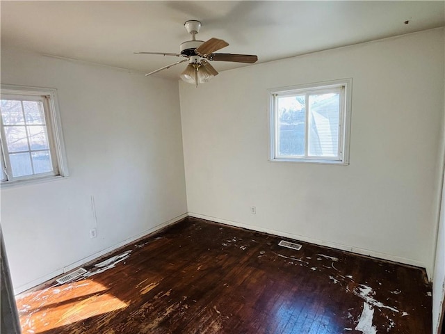 empty room with dark hardwood / wood-style floors, a wealth of natural light, and ceiling fan