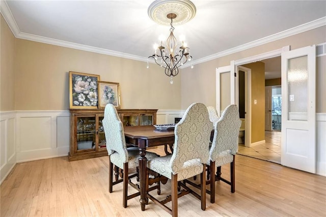 dining space with a chandelier, light wood-type flooring, and ornamental molding