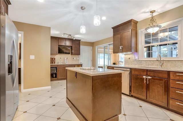 kitchen featuring a center island, sink, tasteful backsplash, decorative light fixtures, and stainless steel appliances