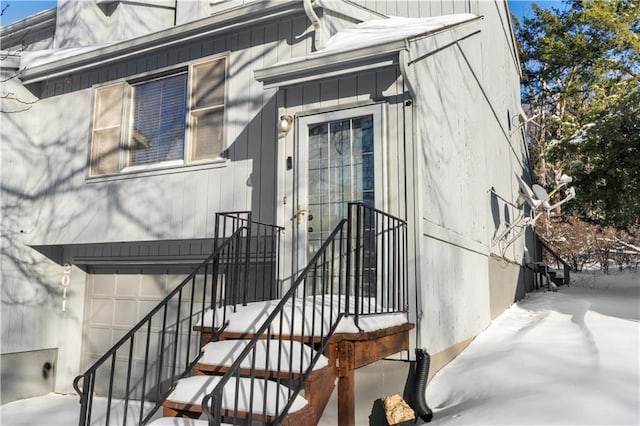 snow covered property entrance with a garage