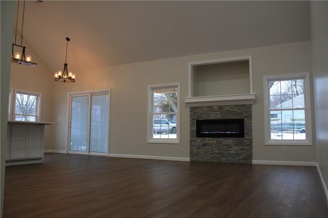 unfurnished living room with lofted ceiling, a stone fireplace, dark hardwood / wood-style floors, and a chandelier