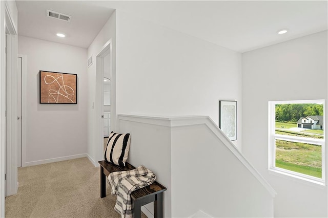 corridor featuring an upstairs landing, visible vents, light colored carpet, and recessed lighting