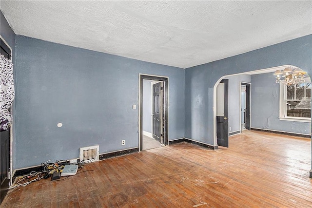 empty room with wood-type flooring and a textured ceiling