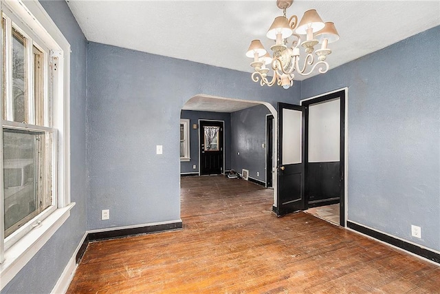 empty room with dark hardwood / wood-style floors and a chandelier