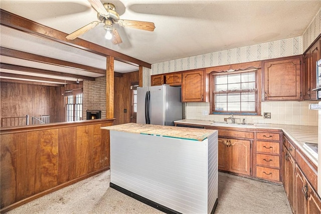 kitchen featuring beam ceiling, stainless steel refrigerator, ceiling fan, sink, and plenty of natural light