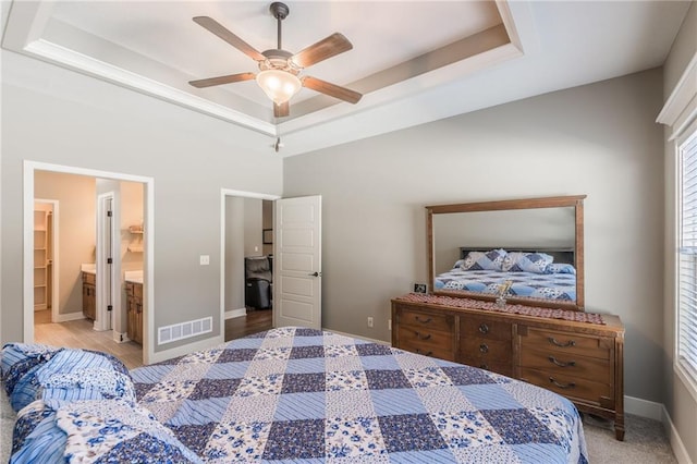 bedroom featuring ensuite bathroom, ceiling fan, and a tray ceiling