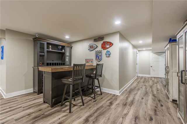 bar with butcher block counters and light wood-type flooring