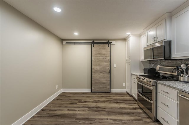 kitchen with white cabinetry, a barn door, dark hardwood / wood-style floors, backsplash, and appliances with stainless steel finishes