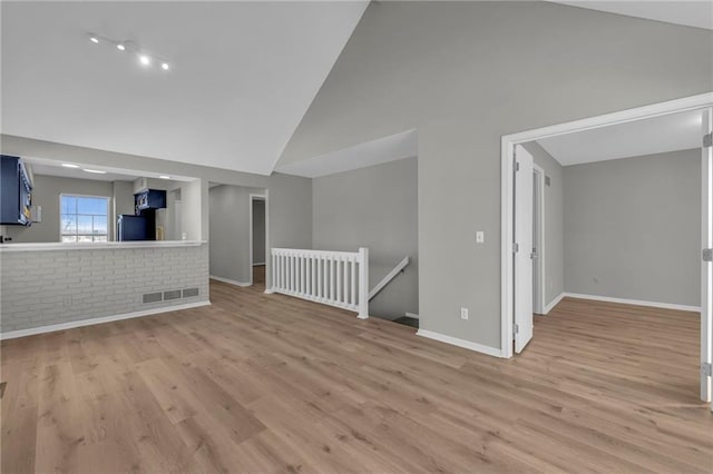 interior space featuring light wood-type flooring and high vaulted ceiling