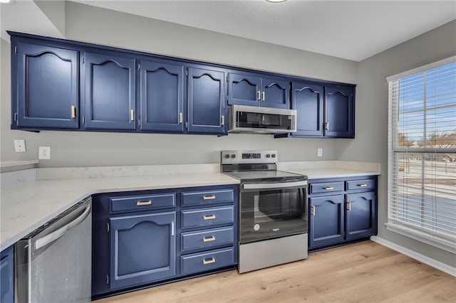 kitchen with light wood-type flooring, blue cabinetry, and appliances with stainless steel finishes