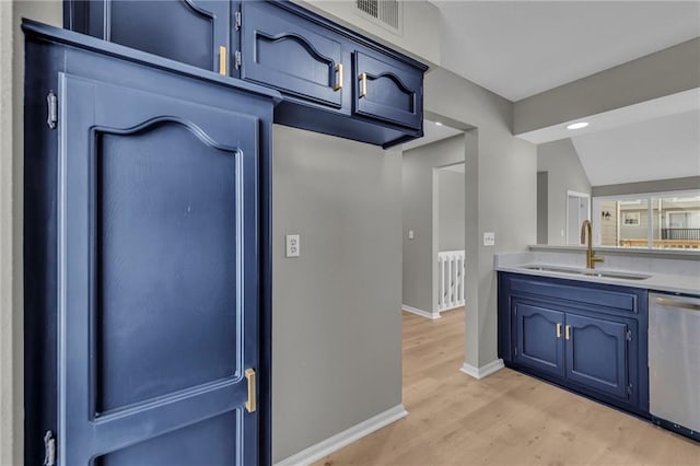 kitchen with light wood-type flooring, vaulted ceiling, sink, blue cabinetry, and dishwasher