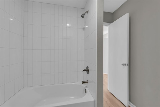 bathroom with hardwood / wood-style floors and tiled shower / bath