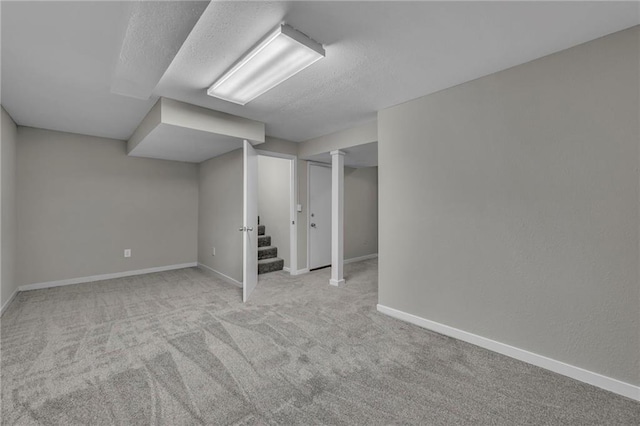 basement featuring light colored carpet and a textured ceiling