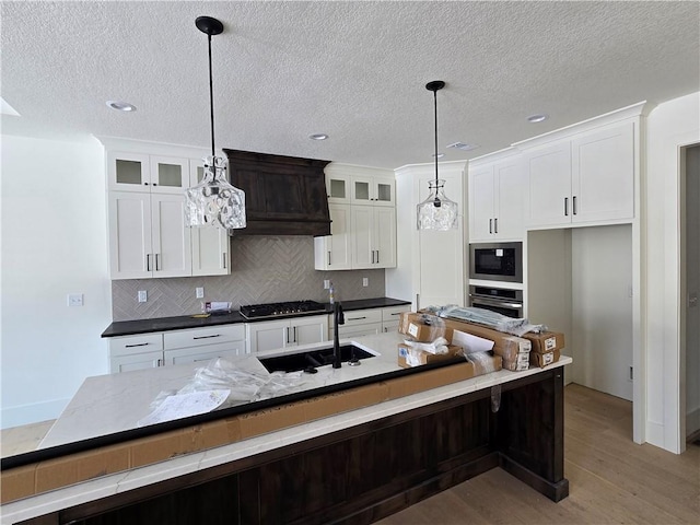 kitchen featuring a sink, light wood-style floors, white cabinetry, decorative backsplash, and built in microwave
