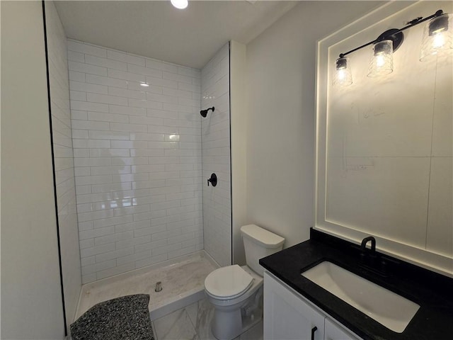 full bathroom with toilet, vanity, and a tile shower