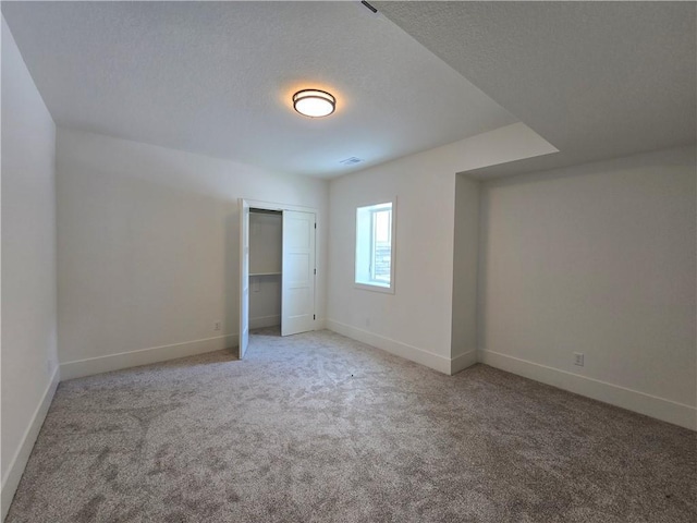 unfurnished bedroom with a textured ceiling, a closet, light colored carpet, and baseboards