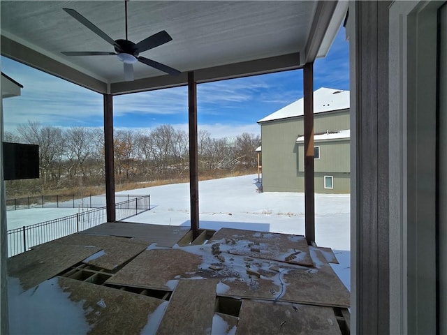 snow covered patio featuring ceiling fan and fence