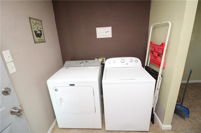 clothes washing area featuring baseboards, laundry area, light tile patterned flooring, and washer and dryer