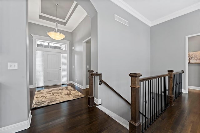 entryway with a raised ceiling, ornamental molding, and dark hardwood / wood-style flooring