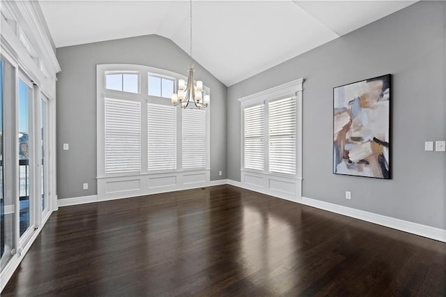 empty room featuring lofted ceiling, plenty of natural light, a notable chandelier, and dark hardwood / wood-style floors