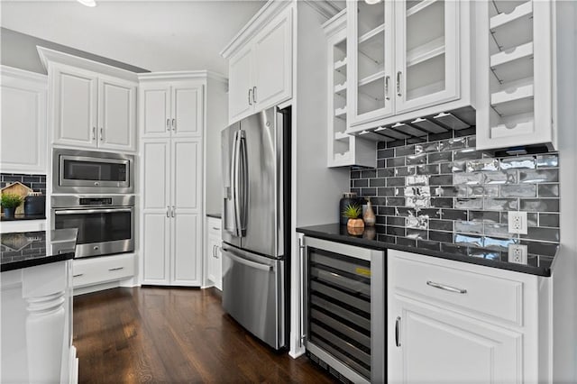 kitchen with wine cooler, dark wood-type flooring, appliances with stainless steel finishes, decorative backsplash, and white cabinets