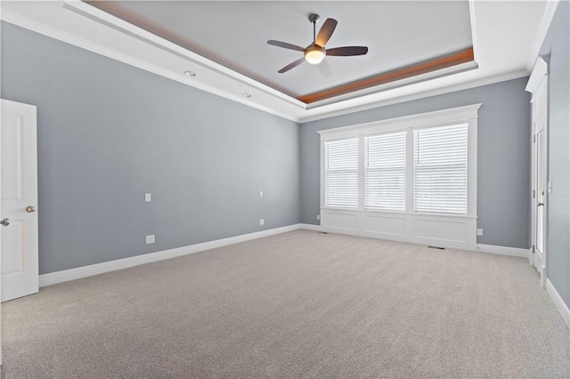 empty room with crown molding, light carpet, ceiling fan, and a tray ceiling