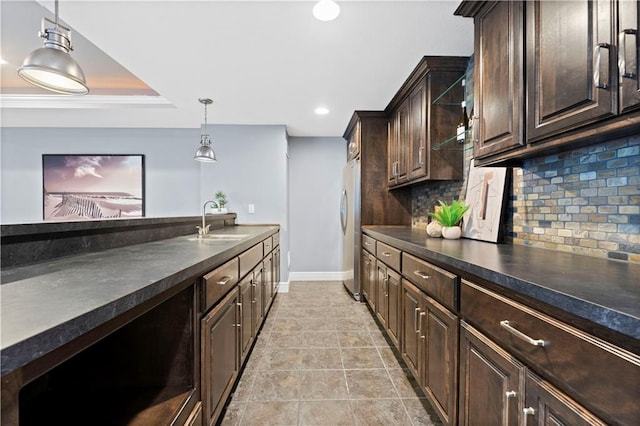 kitchen with pendant lighting, tasteful backsplash, sink, stainless steel fridge, and dark brown cabinetry