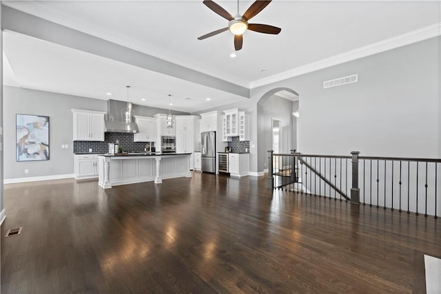 unfurnished living room featuring crown molding, dark wood-type flooring, and ceiling fan