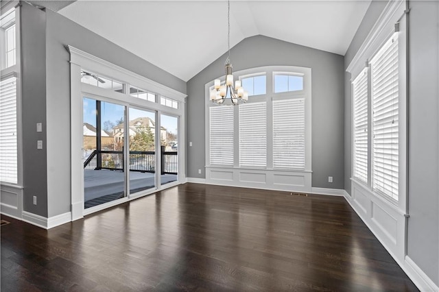 unfurnished dining area with dark hardwood / wood-style flooring, vaulted ceiling, and an inviting chandelier