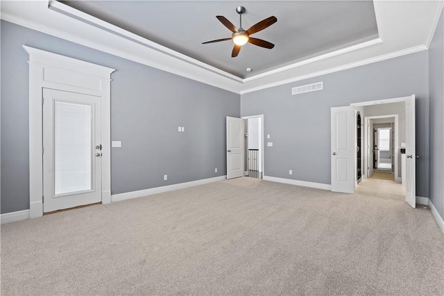 empty room featuring a raised ceiling, crown molding, light colored carpet, and ceiling fan