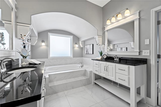 bathroom with tiled tub and vanity