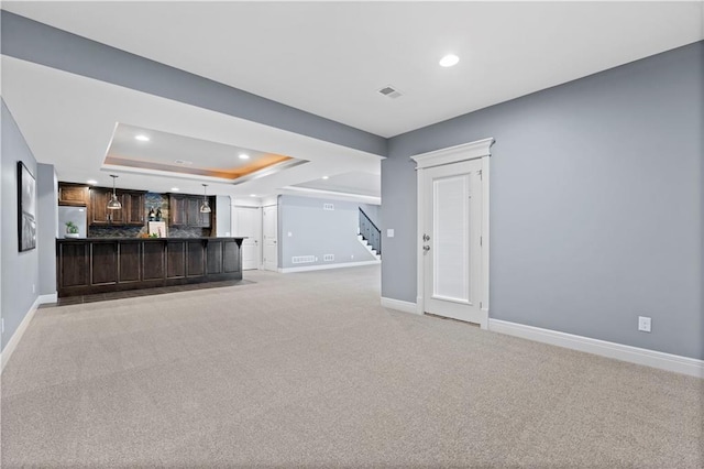 unfurnished living room featuring a tray ceiling and light colored carpet