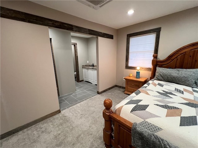 bedroom featuring light colored carpet, ensuite bath, and sink