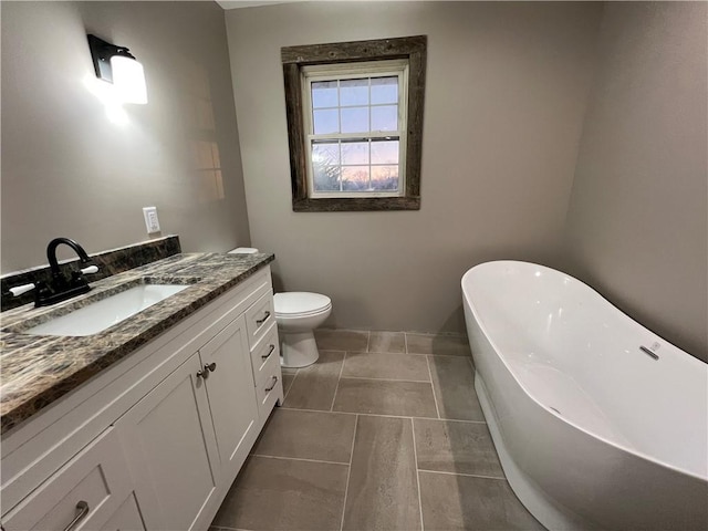 bathroom featuring tile patterned flooring, vanity, toilet, and a tub