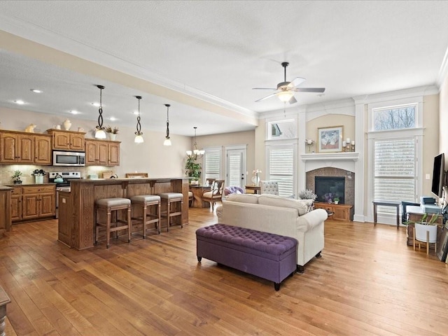 living room with ceiling fan with notable chandelier, a wealth of natural light, and light wood-type flooring